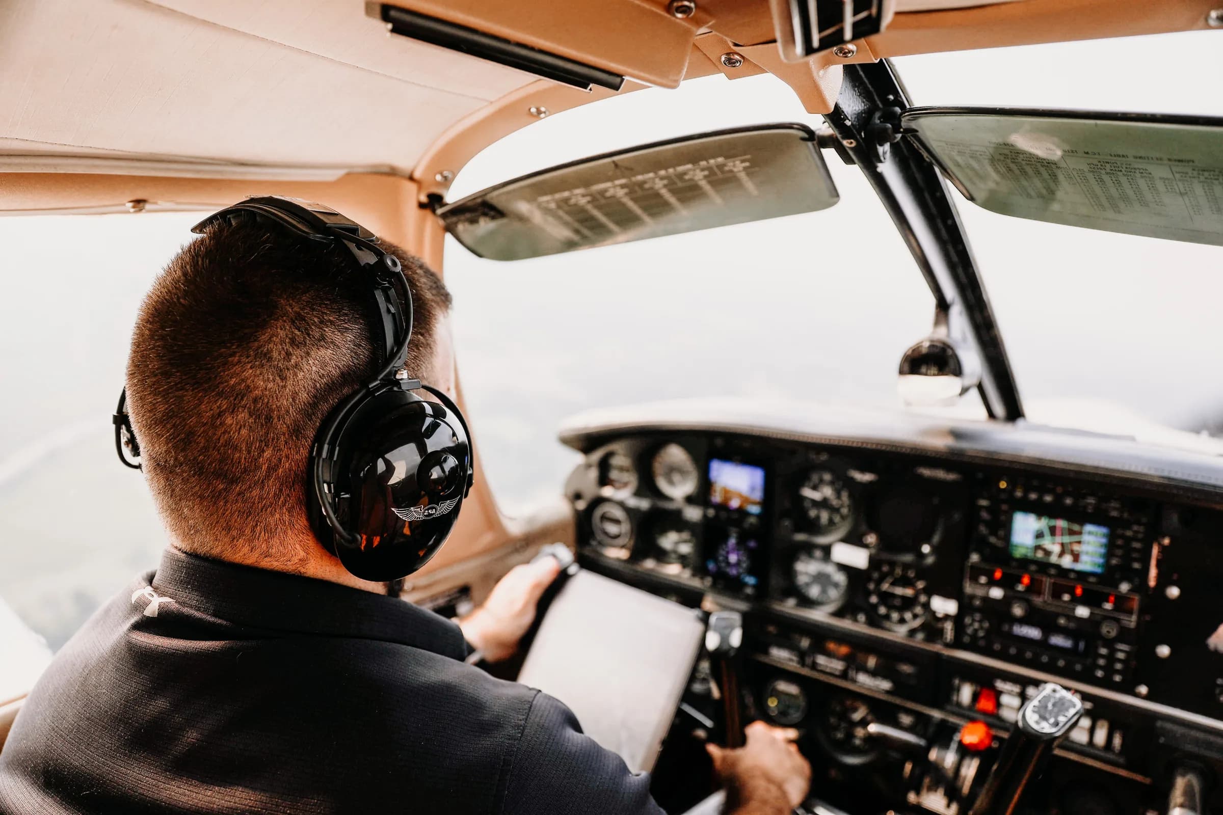 Piloot met aviation headset aan de stuurknuppel van een klein lesvliegtuig