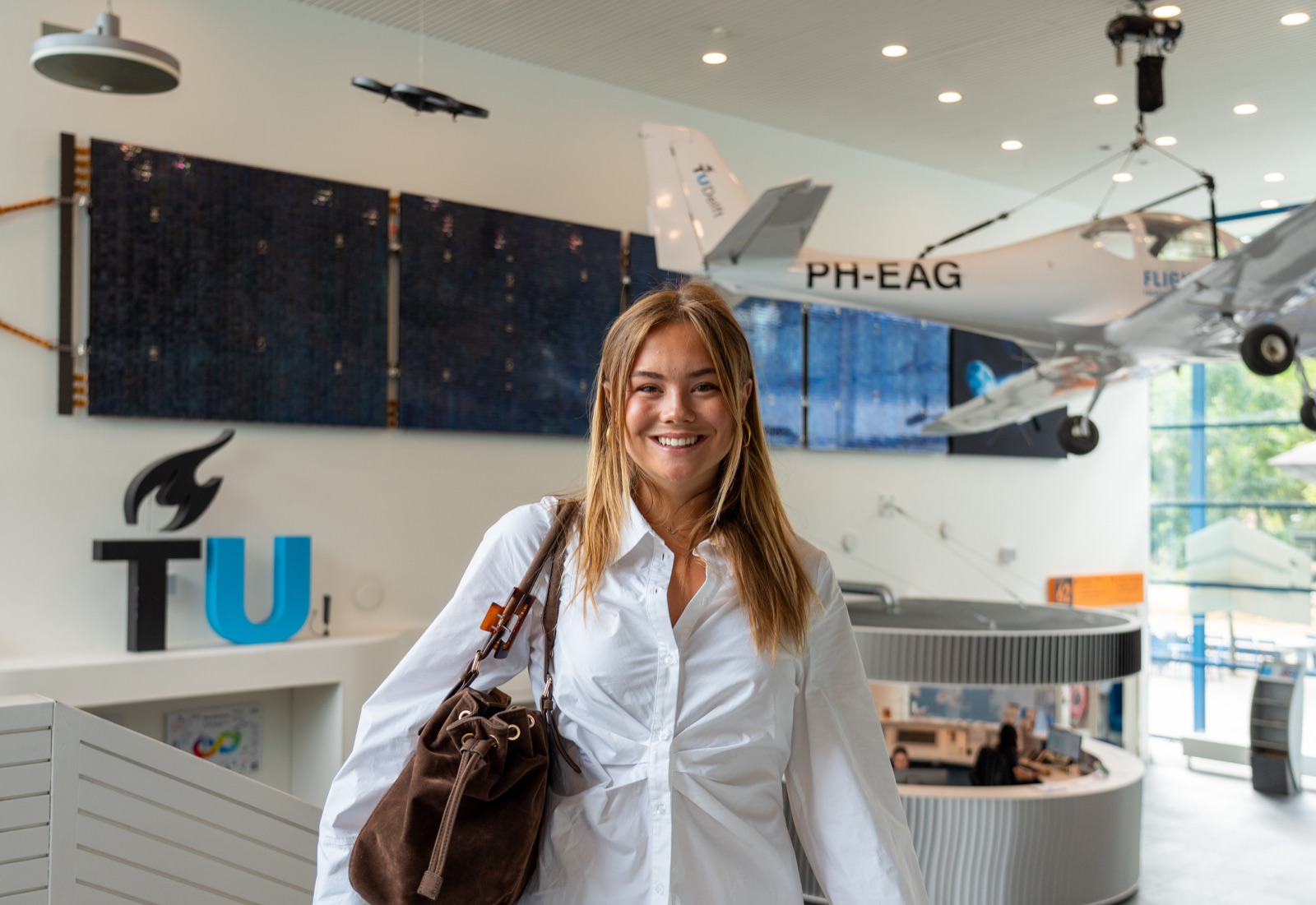 Prinses Ariane in de hal van de faculteit Luchtvaart- en Ruimtevaarttechniek van de TU Delft, met een vliegtuig aan het plafond