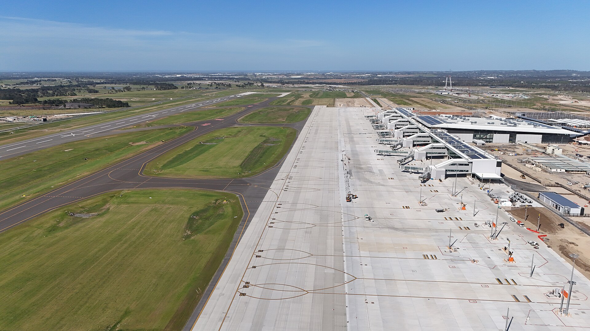 Luchtfoto van Western Sydney International Airport vanaf het zuiden met de baan, het platform en de terminal onder een blauwe lucht
