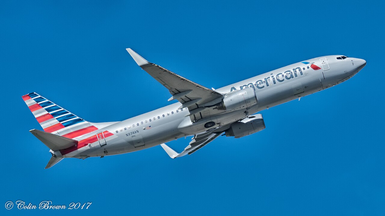 Een zilverkleurige Boeing 737-800 van American Airlines met registratie N974AN klimt met ingetrokken landingsgestel tegen een strakblauwe lucht