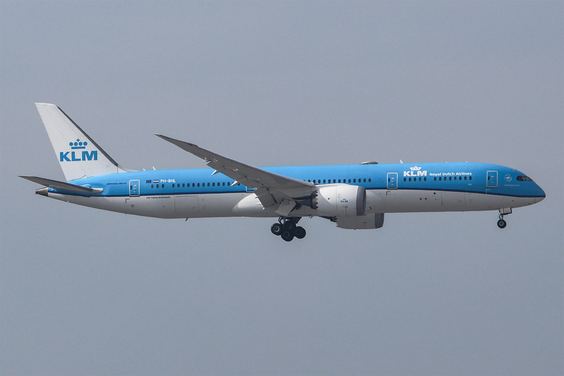 Een blauw-witte Boeing 787-9 van KLM met registratie PH-BHL in de landing, met uitgeklapt landingsgestel tegen een grijze lucht