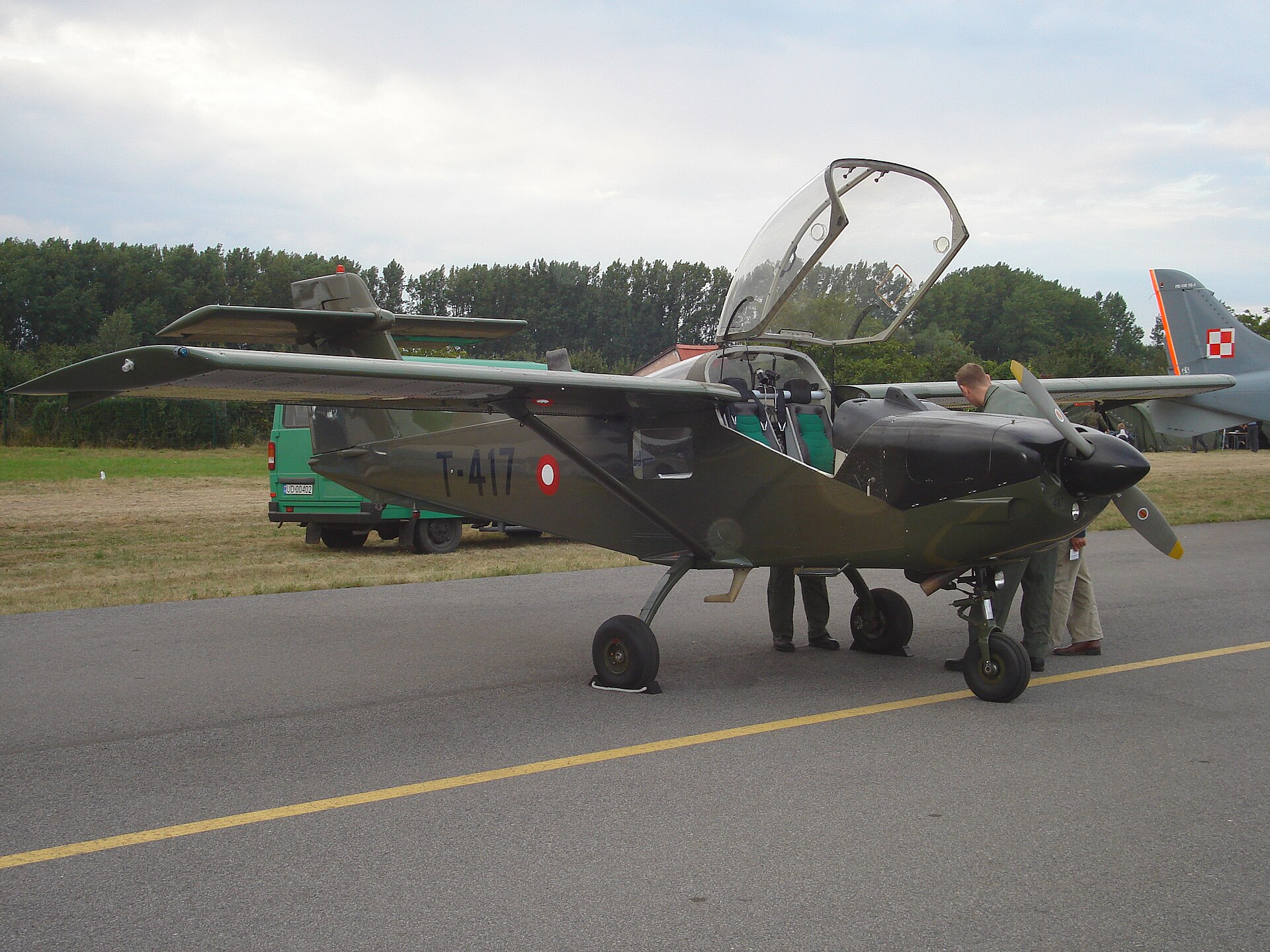 Een groen geschilderd lesvliegtuig van het type Saab MFI-17 Supporter met hoge vleugel, vast landingsgestel en geopende cockpitkap staat op een platform